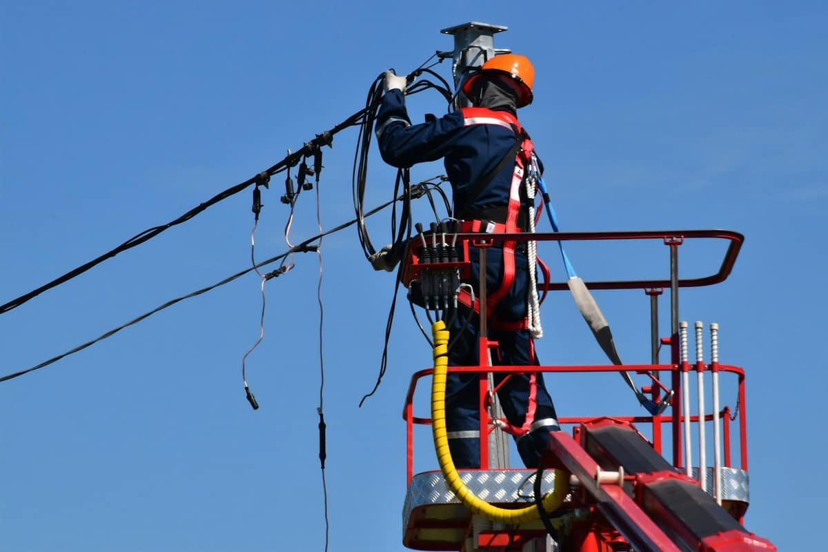 Utility worker repairing overhead power lines
